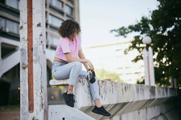 Une Jolie Jeune Femme Aux Cheveux Bouclés Assise Extérieur Tenant — Photo