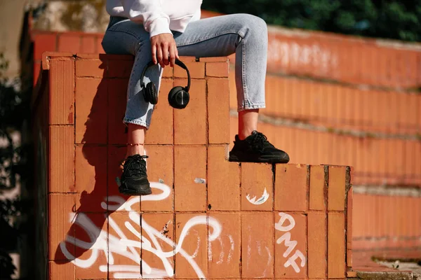 Обрізана Картина Молодої Жінки Яка Сидить Цегляній Стіні Тримає Навушники — стокове фото