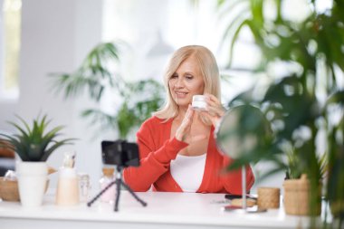 Yaşlı bir vlogger evde oturuyor ve yeni anti-yaş kreminden bahsediyor..