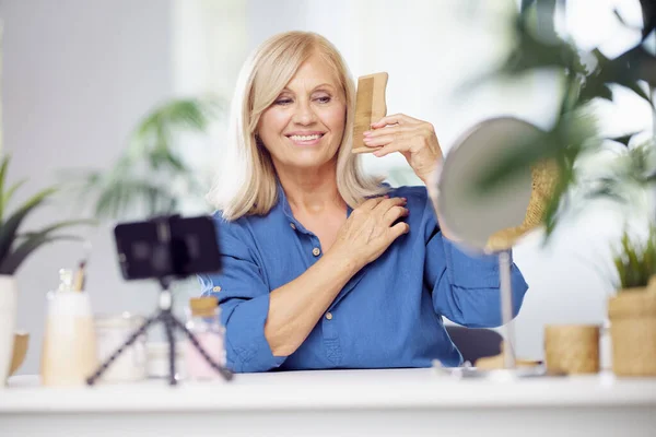 Een Gelukkige Blonde Oudere Vrouw Zit Thuis Haar Haar Kammen — Stockfoto