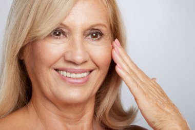 Güzel, yaşlı bir bayanın buruşuk tenine dokunuşunun yakın çekimi. Güzellik fotoğrafçılığı