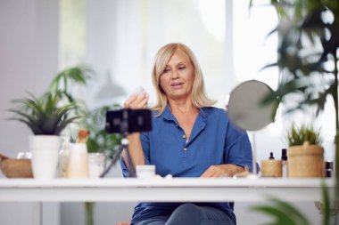 Yaşlı bir vlogger evde oturup yeni anti-yaş kreminden bahsediyor. Önplana odaklan