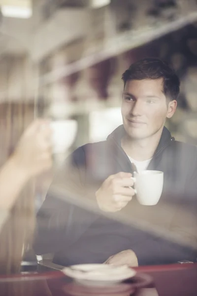 Man with coffee cup looking through window in cafe — Stock Photo, Image