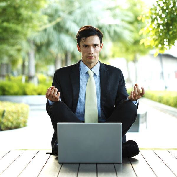 Businessman meditating in lotus pose