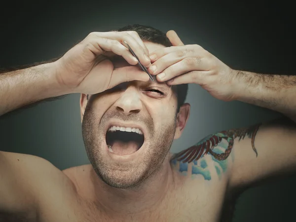 Tatuado homem arrancando sobrancelhas — Fotografia de Stock