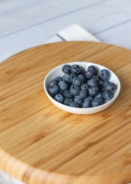 Tahta masadaki beyaz kasede taze yaban mersini. Yabanmersinine odaklan. Fotoğrafı kapat. Kırsal tarzda. Sağlıklı gıda konsepti.