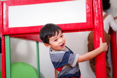 Neşeli çocuk, sevimli Asyalı çocuk, oyun alanında eğleniyor, küçük çocuk arkadaşıyla oynuyor..  