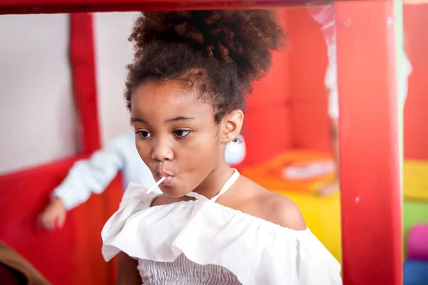 Kıvırcık Saçlı Tatlı Şeker Yiyen Sevimli Afrikalı Amerikalı Kızın Portresi — Stok fotoğraf