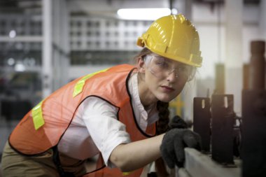 Kasklı ve güvenli gözlükler takan endüstriyel mühendis kadın, fabrika fabrikasında enstrümanla çalışıyor, endüstride çalışan genç ve güzel bir kadın.