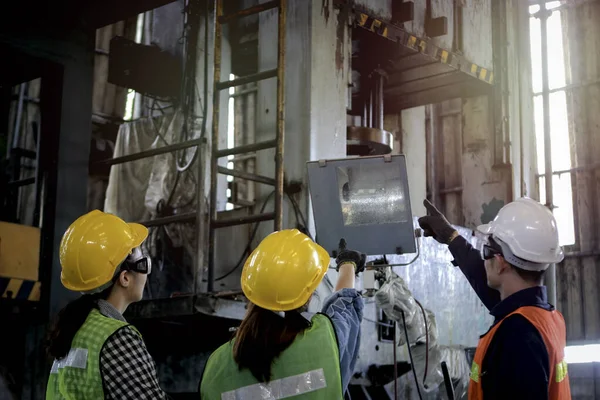 Group of Industrial engineer worker wearing helmet and safe glasses discussing and planning, pointing something at manufacturing plant factory, young people working in industry