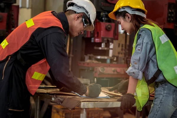 Industrial engineer worker people wearing helmet discussing and planning at manufacturing plant factory, young woman and man working in industry