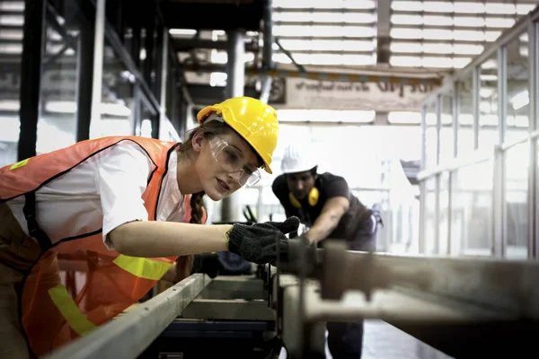 Industrial engineer worker wearing helmet and safe glasses, working with instrument at manufacturing plant factory, young beautiful woman working in industry