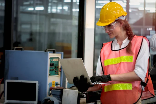 Industrial engineer worker wearing helmet and safe glasses, holding laptop compute, working with instrument at manufacturing plant factory, young beautiful woman working in industry