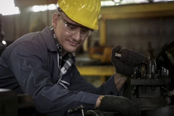 Industrial engineer worker wearing helmet and safe glasses  operating with machinery at manufacturing plant factory, working with machine in industry concept