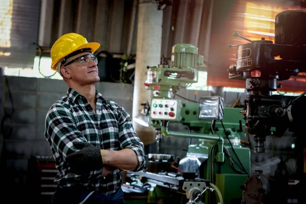 Industrial engineer worker wearing helmet and safe glasses  operating with machinery at manufacturing plant factory, working with machine in industry concept