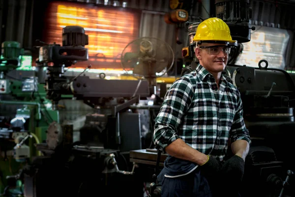 Industrial engineer worker wearing helmet and safe glasses, operating with machinery at manufacturing plant factory, working with machine in industry concept