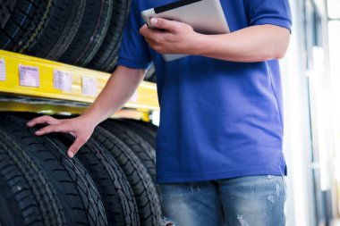 Otomobil tamircisi araç tamirhanesinde tekerlekleri kontrol ediyor, garajda çalışan bir adam, araba servisi teknisyeni otomobil servis merkezindeki depo stoklarını kontrol ediyor..