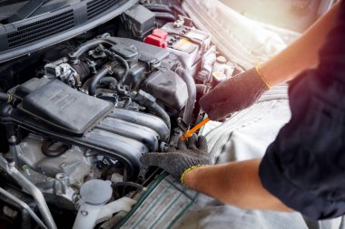 Auto mechanic hand working with engine in garage, car service technician repairing customer car at automobile service center, inspecting car suspension and engine system, vehicle repair service shop.