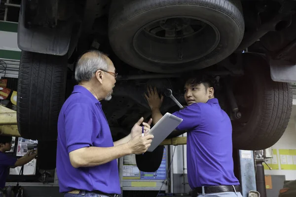 Two Mechanic Checking Wheel Inspecting Car Body Suspension System Garage — Stockfoto