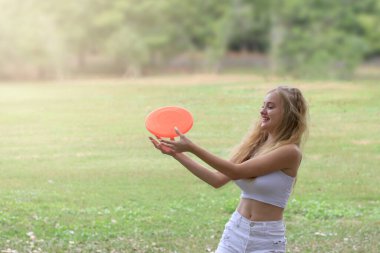 Genç ve mutlu bir kız, yaz bahçesinde arkadaşlarıyla vakit geçirirken frizbiyle eğleniyor.. 
