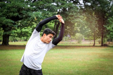 Genç koşucu egzersiz yapmadan önce vücudunu esnetiyor parkta koşuyor, sporcu erkek koşucu antrenmanı yapıyor ve bahçede egzersiz yapıyor. 