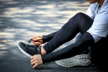 Spor ayakkabılarla ayakkabı bağlama, koşu antrenmanı ve parkta egzersiz yaparken atlet.