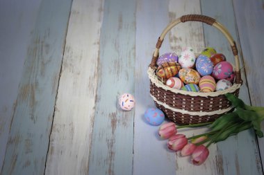 Ahşap masada lale çiçekli Paskalya yumurtaları, arka planda renkli yumurtalar, festival ve tatil bahar kameraları, Paskalya kalibreleri.