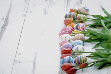 Ahşap zemin üzerinde lale çiçekleri olan renkli Paskalya yumurtaları, festival ve tatil baharı geliyor, Paskalya kalibrasyonu