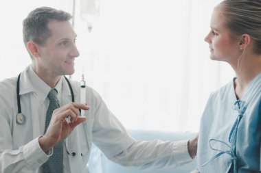 Doktor şırıngayı genç, güzel hastaya, sağlık hizmetine ve hastane konseptine enjekte etmeye hazır tutuyor..