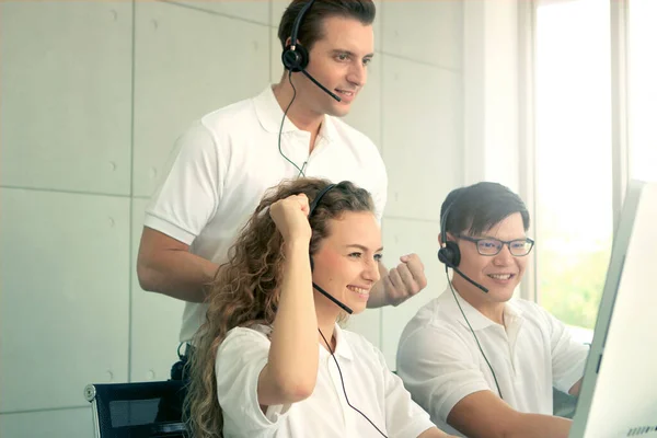 Happy smiling young beautiful woman with headphones work at call center desk consultant raised arm up, supervisor motivate team to improve customer service when talk with client on hands-free, teamwork service mind