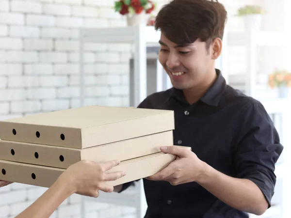 Hands deliver the goods to the recipient customer. Young man receiving delivery pizza box, shipping and courier delivery services express concept.