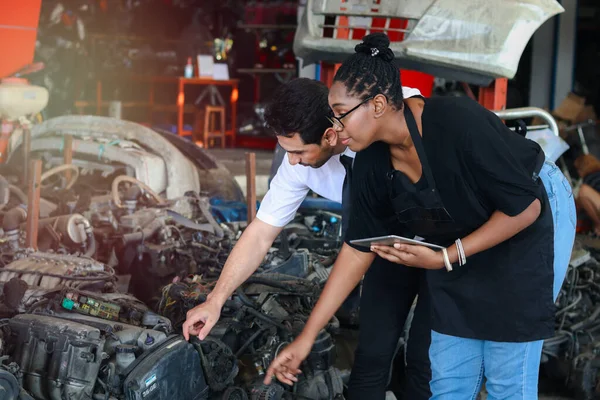 Happy Harmony people at workplace, smiling white man and African American worker working together, two people checking product stock at auto spare parts store shop warehouse with many second hand engine parts as blurred background