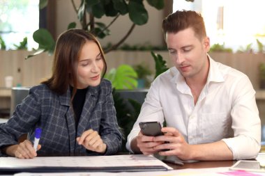 Modern ofis ya da kahve dükkanının lobisinde oturan mutlu iş arkadaşı, birlikte çalışan çekici iş ortağı, iş projesi hakkında sohbet eden ve tartışan. 