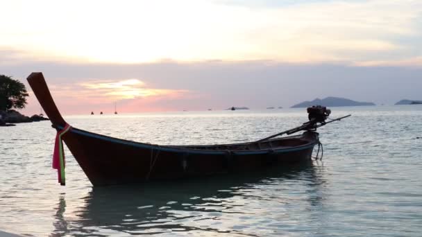 Tradiční longtail loď plovoucí na mořské vodě za večerního soumraku západ slunce s dramatickou orangovou oblohou, krásná relaxační scéna tropické letní mořské pláže, ostrov Koh Lipe, Thajsko. 