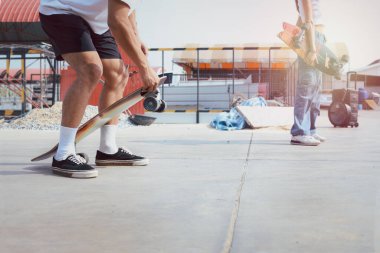 Güneşli bir günde oynayan genç bir adamla yakın çekim sörf tahtası. Erkekler açık havada kaykay sporlarıyla eğleniyor..