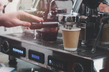 Kahveci elleri sıcak kahve hazırlarken, garsonlar kahve tezgahında kahve makinesiyle çalışırken..