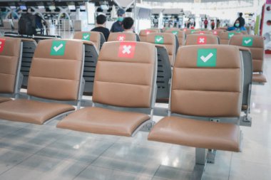 Boş koltuklar sırası kırmızı üzerinde çapraz işaret ve sosyal uzaklık fikri için yeşil işaretleri gösteriyor. Uçak beklerken Coronavirus (covid19) enfeksiyonunu önlemek için turist ve yolculardan uzak durun.