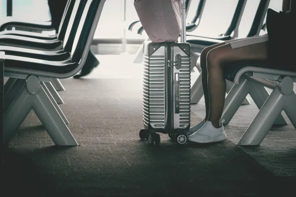 スーツケースの荷物と女性の足は 空港の空いている出発ホールで椅子に座って フライト遅延キャンセル 旅行や休暇のコンセプトを待っています — ストック写真