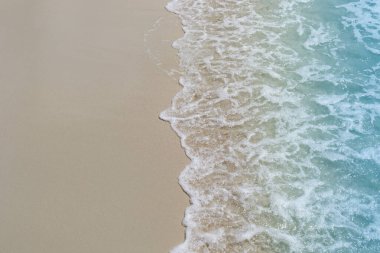 Tropikal yaz kumsal arka planının güzel doğal manzarası. Mavi okyanus dalgaları beyaz kumsal adasına çarpıyor..