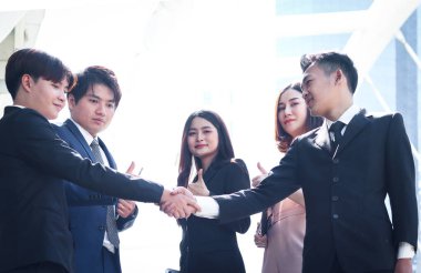 Genç Asyalı başarı grubu başarılı iş adamları imza üstüne imza atarak el sıkışıyor, şirket grubu başparmak sallıyor ve iyi sonucu takdir ediyor, iş adamı ve kadın şehir dışında buluşuyorlar..