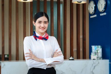 Gülümseyen güzel Asyalı kadın resepsiyonistin portresi otel resepsiyonunda kolları çapraz duran, otel servisine tatil konsepsiyonunu kontrol edin..  