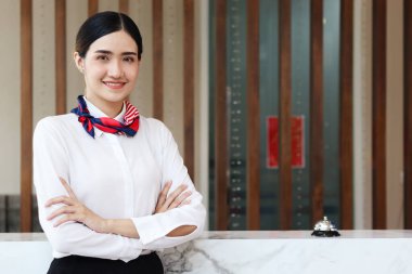 Gülümseyen güzel Asyalı kadın resepsiyonistin portresi otel resepsiyonunda kolları çapraz duran, otel servisine tatil konsepsiyonunu kontrol edin..  