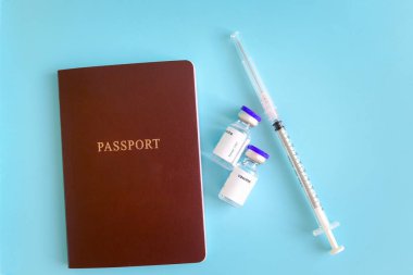 Aşı tüpleri ve mavi arka planda iğne şırıngası olan pasaport, Coronavirus covid-19 aşısı olan gezginlerin tatil gezisinde güvenlik seyahati.. 