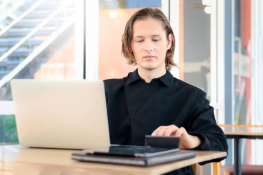 Genç ve yakışıklı garson kafenin camlarını silmek için sprey tutuyordu. Restoranı temizliyordu. Gülümseyen işçi kameraya doğru püskürtüyordu..