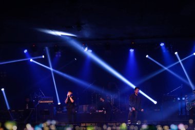 Şarkıcı ve müzisyen, müzik festivalinde rock konserinde, renkli parlak spot ışıkları, bokeh ve karanlık arka planda sigara dumanı.