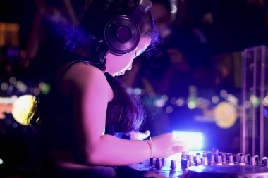 Küçük kız DJ canlı sette müzik çalıyor ve kontrol tablosu konsolunda müzik karıştırıyor. Gece kulübü sahnesinde karıştırma masası, müzik plajı parti festivali ve gece hayatı konsepti..