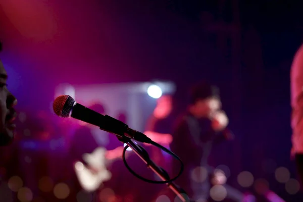 Close up of microphone for singer artist on stage with lighting bokeh at concert hall or conference room.