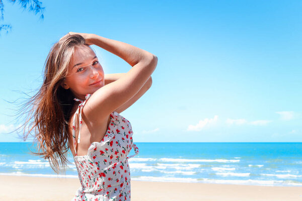 Portrait of smiling young beautiful woman with blond long hair standing on tropical blue sea summer beach, relaxing vacation summer concept.