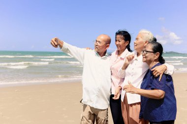 Dört yaşlı, kıdemli arkadaştan oluşan bir grup birlikte dışarı çıkıyor, cep telefonuyla selfie çekiyor, kumsalda eğleniyor ve tatilde dinleniyor ve dinleniyor..