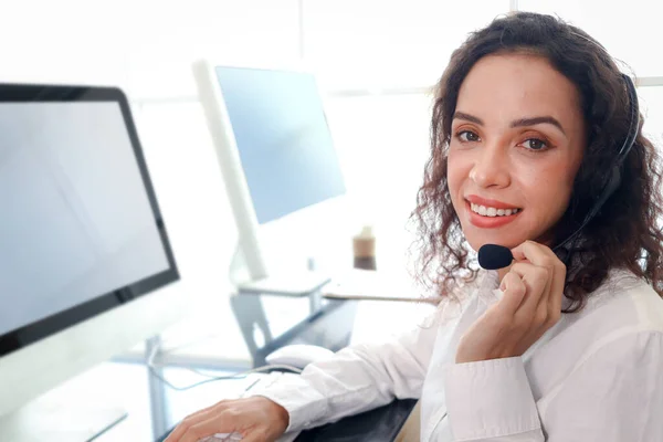 Smiling beautiful woman with headphones work at call center service desk consultant, call center agent with headset talk with customer on hotline, operator with hands-free phone has conversation.